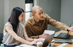 Man and women with laptop computers. Man pointing to computer.