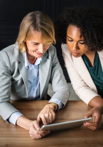 two women looking at a tablet, one pointing to tablet