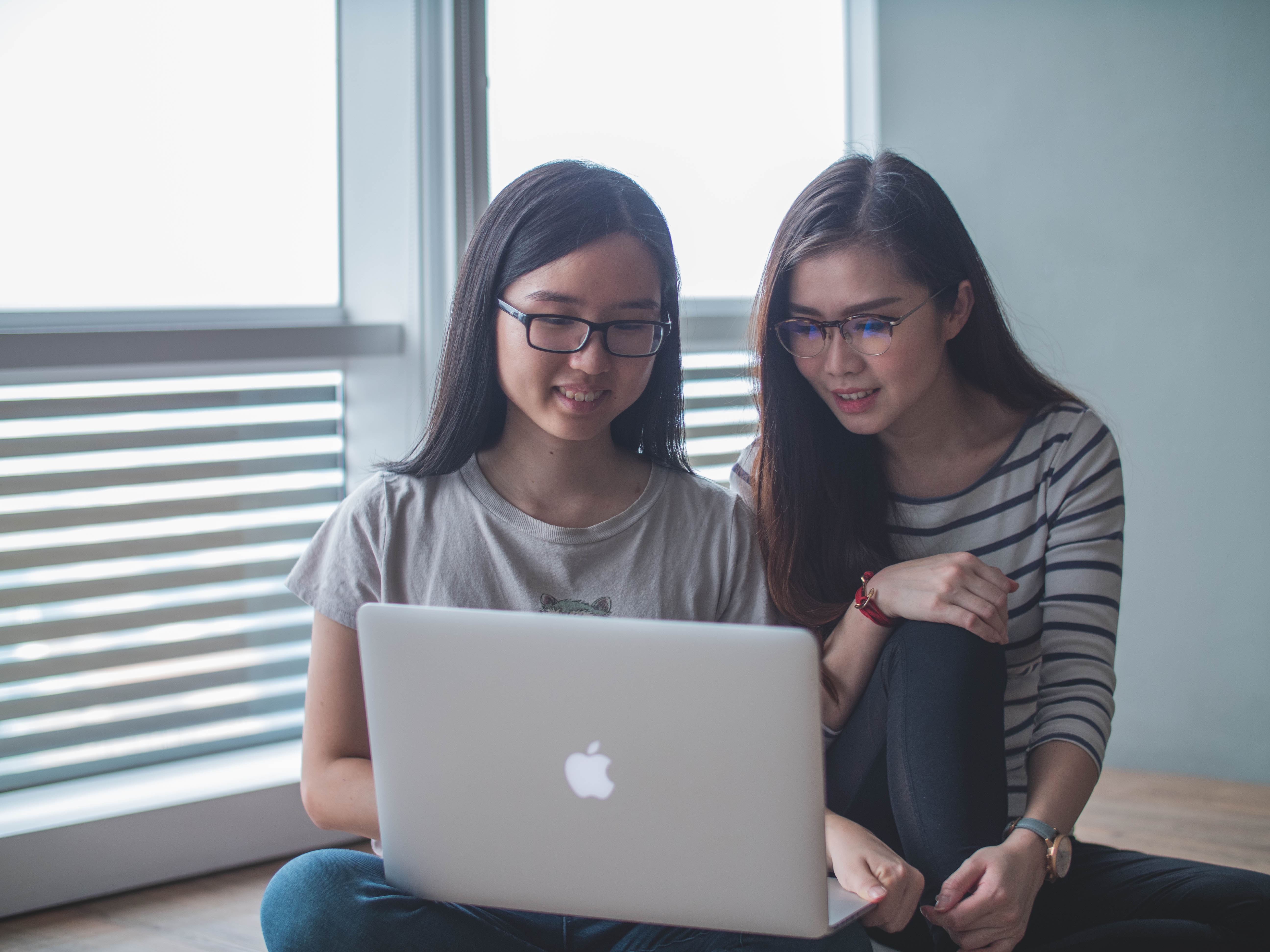 Two Young Women Using A Computer With One Pointing At Screen