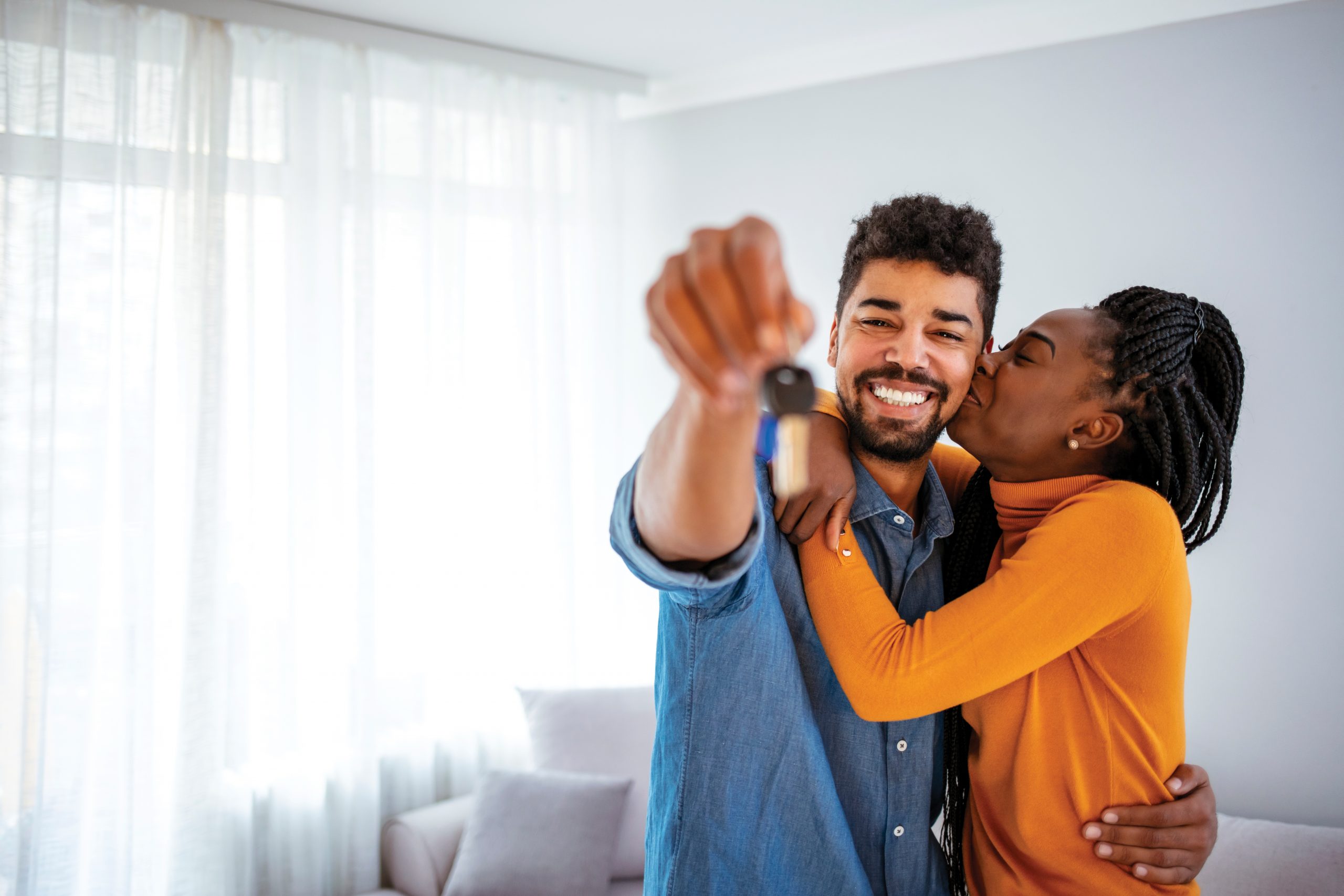 Man Smiling Holding House Keys And Woman Kissing On Cheek